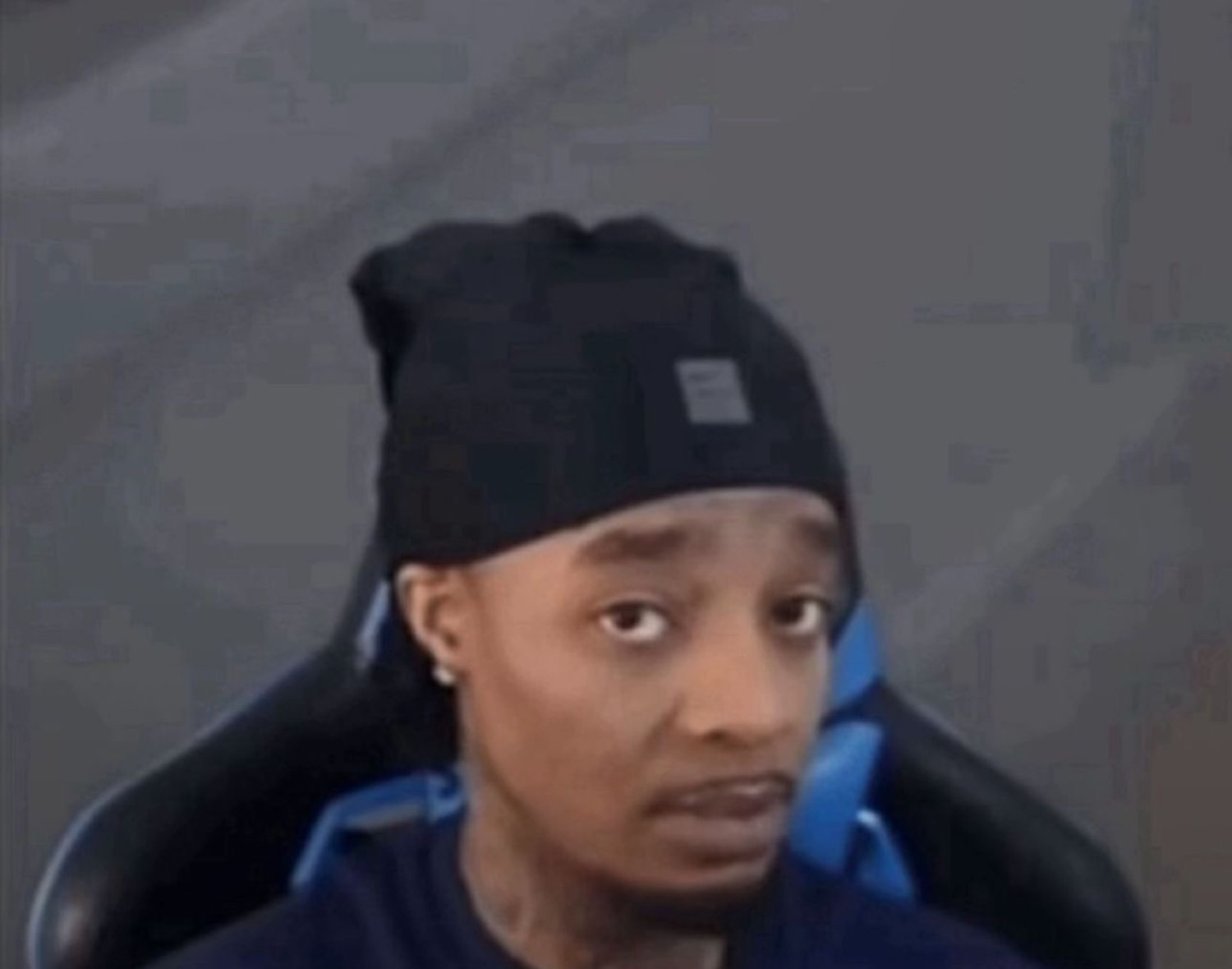 Guy in a beanie slouched in a gaming chair giving a skeptical side-eye