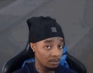 Guy in a beanie slouched in a gaming chair giving a skeptical side-eye