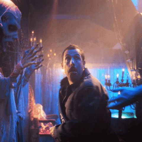 Terrified man in a dark candlelit mansion spraying a can at a ghost