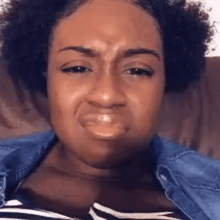 Woman on a couch scrunching her face into a deeply disgusted, unimpressed grimace