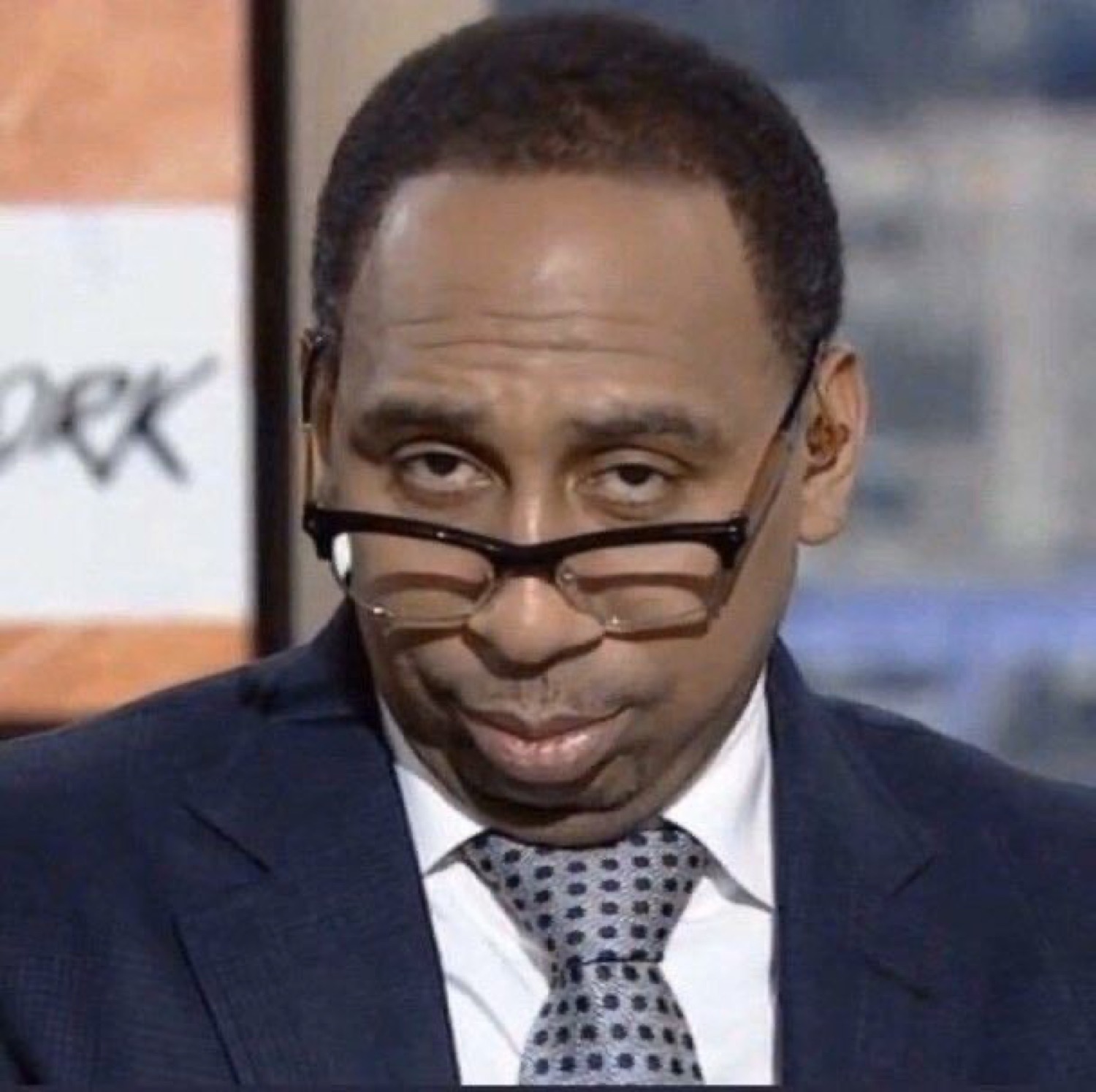 Stephen A. Smith peering over his slipping glasses with a slow-burn side-eye stare