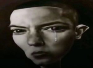 Dramatic grayscale portrait of a person with a single tear rolling down their face and a hard stare