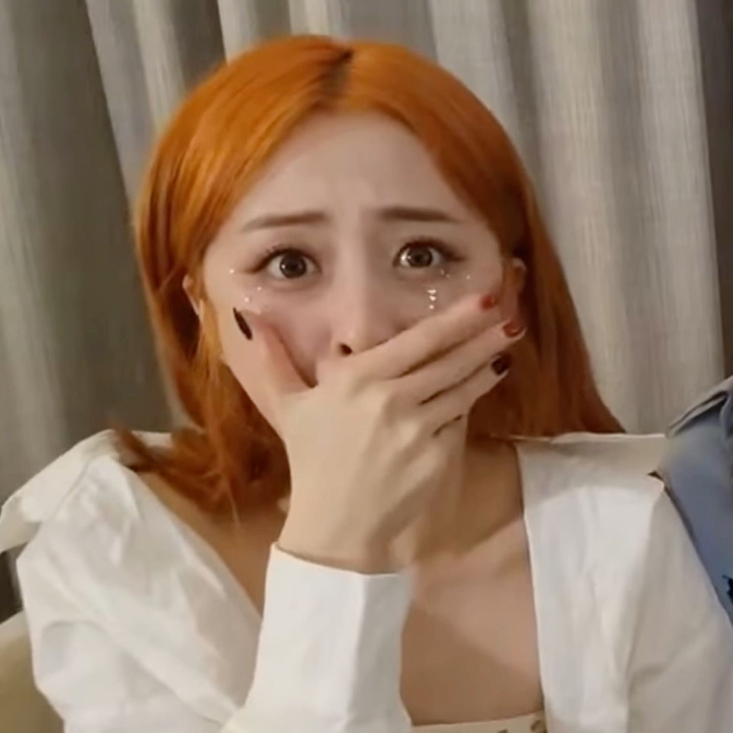 Young woman with orange hair crying and covering her mouth with her hand
