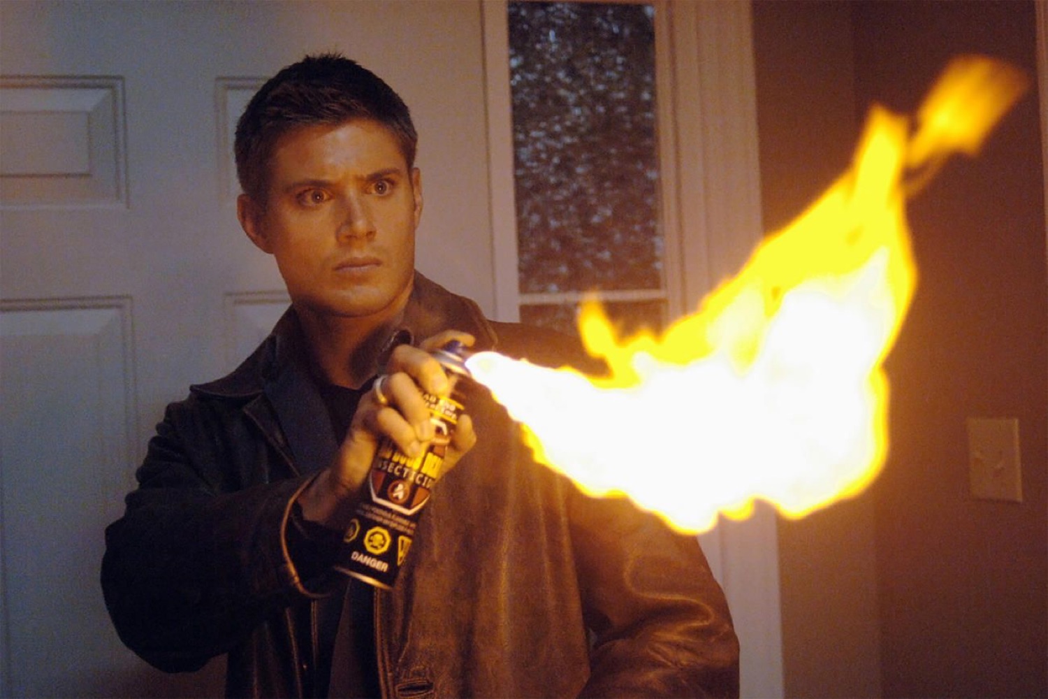 Man aiming a homemade flamethrower with a tense, alarmed look