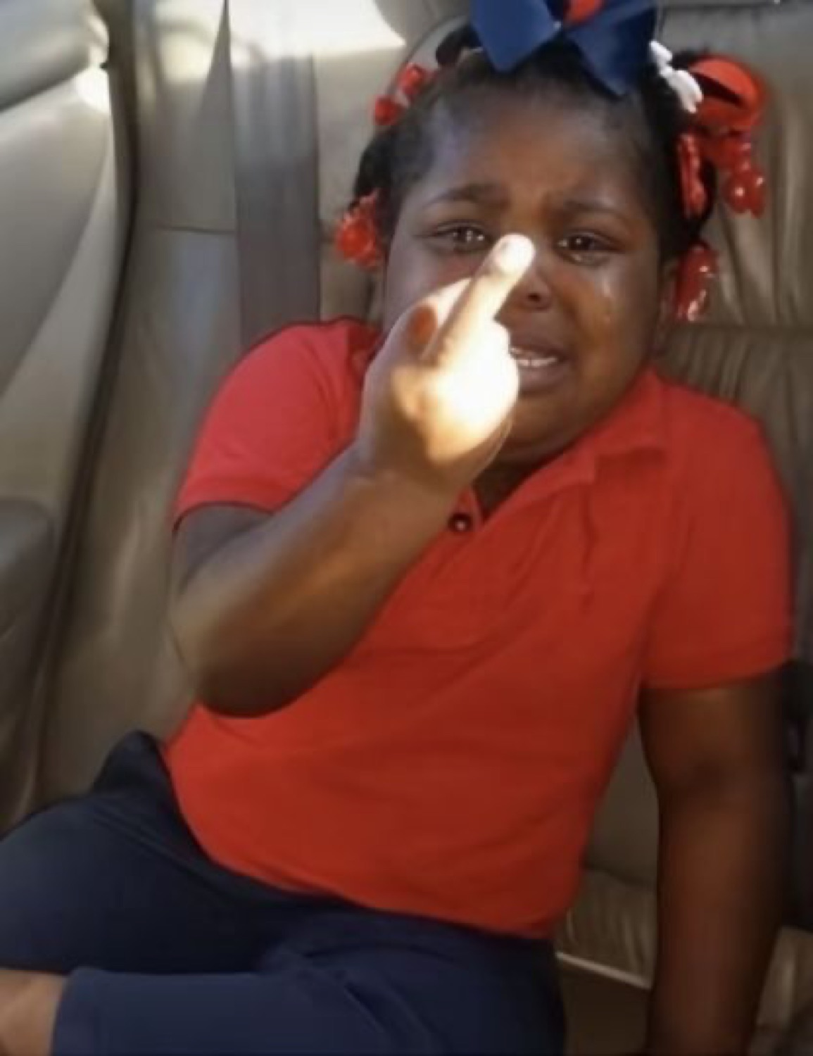 Girl in a car crying her eyes out while jabbing an accusing finger at the camera