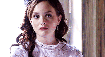 Young woman in a lace top glancing sideways with a cool, judging look