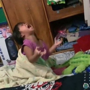 Toddler kneeling on a bed, head tilted back mid-wail in a full dramatic meltdown