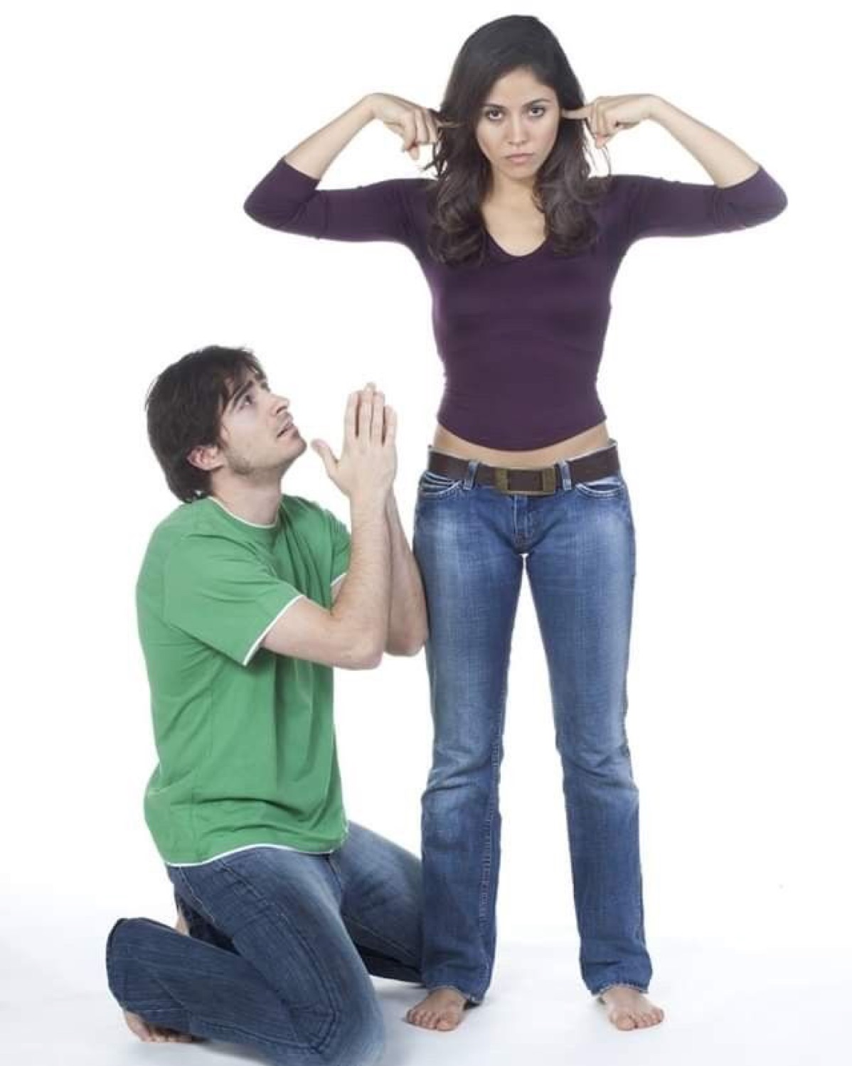 Man on his knees begging while a woman plugs her ears and looks away
