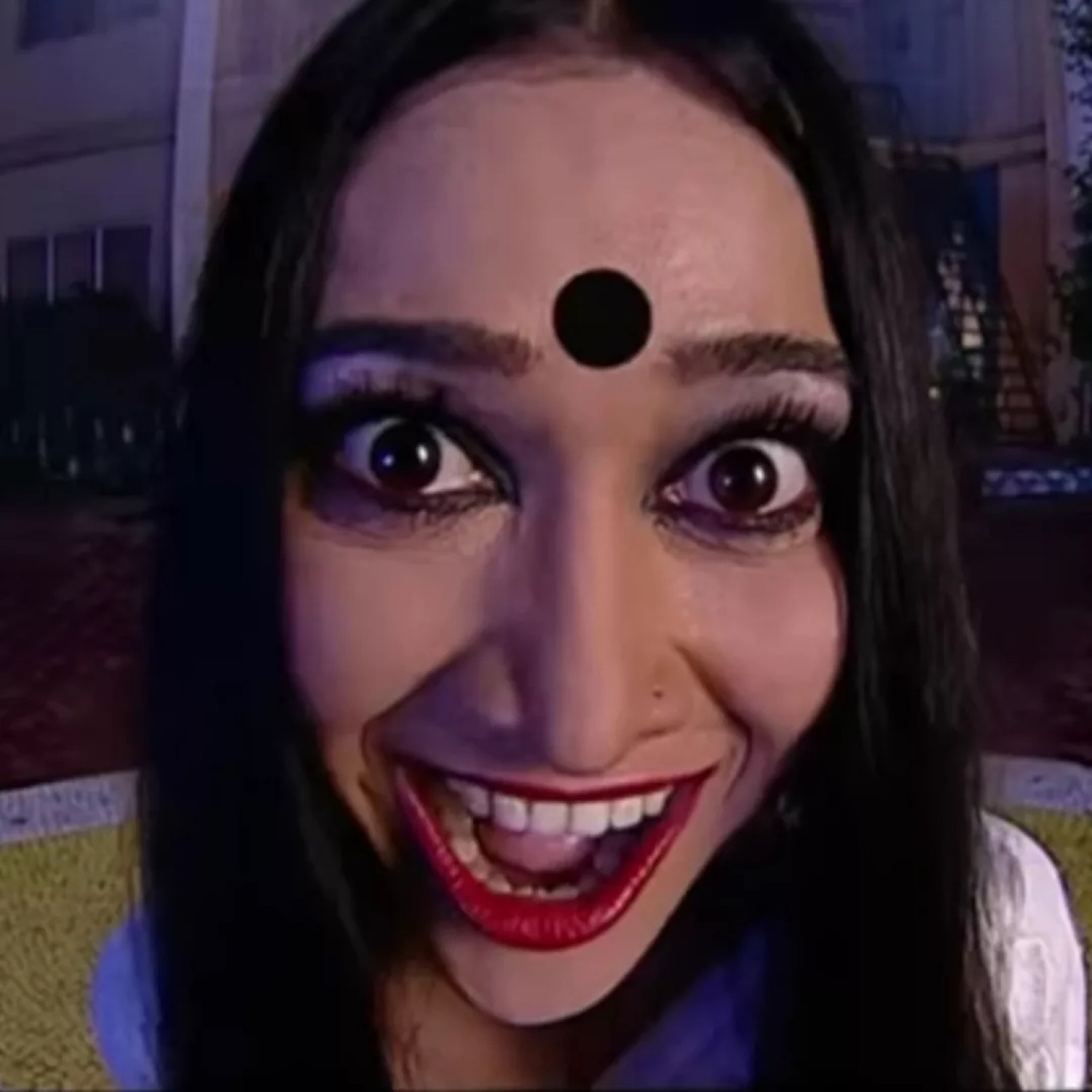 Woman with a big bindi and a wide, unhinged grin