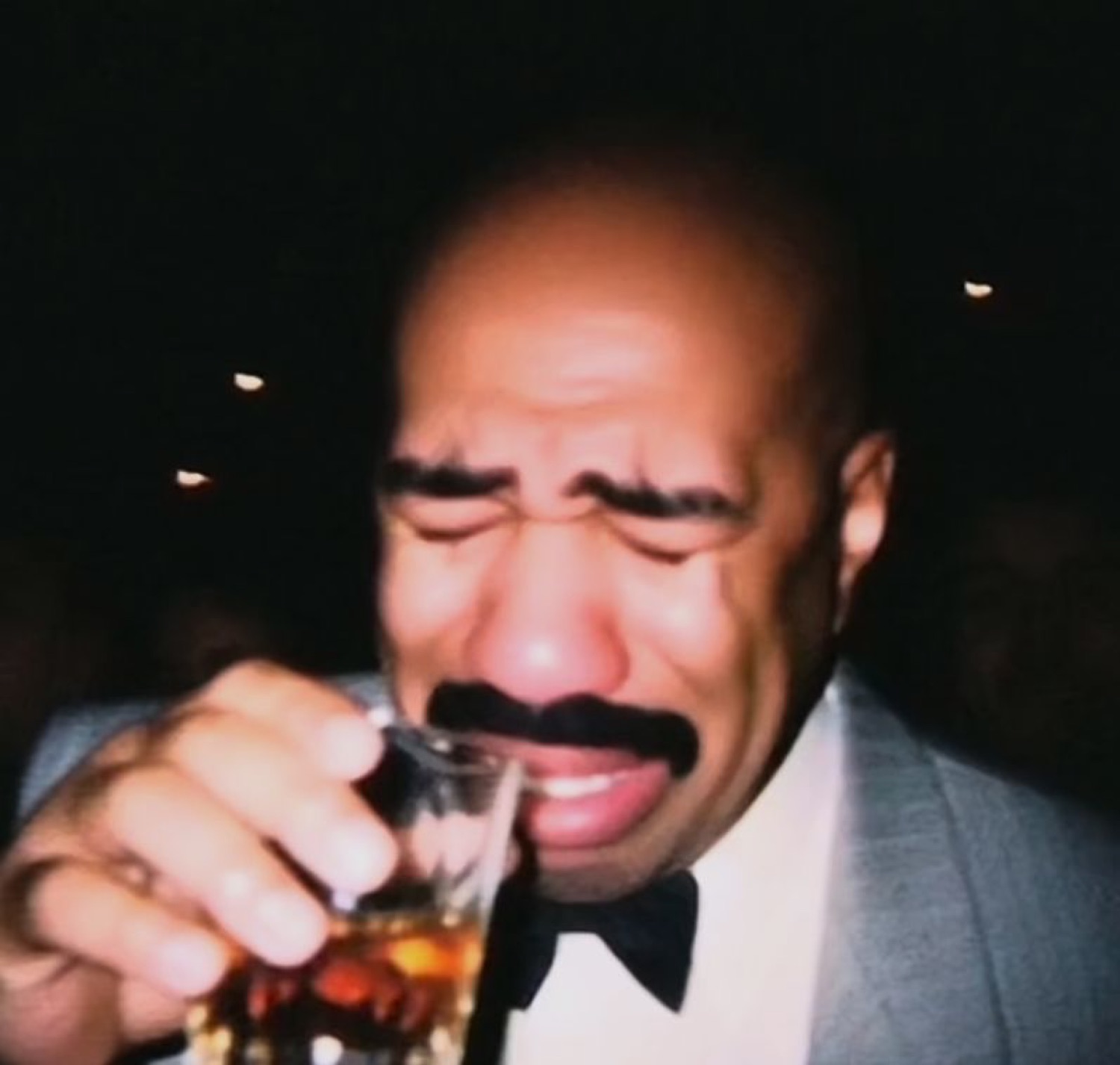 Steve Harvey crying while holding a shot glass, overwhelmed with emotion