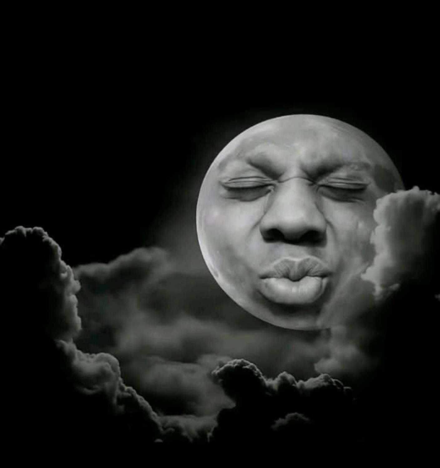 Black-and-white moon with a human face puckering up for a kiss above the clouds