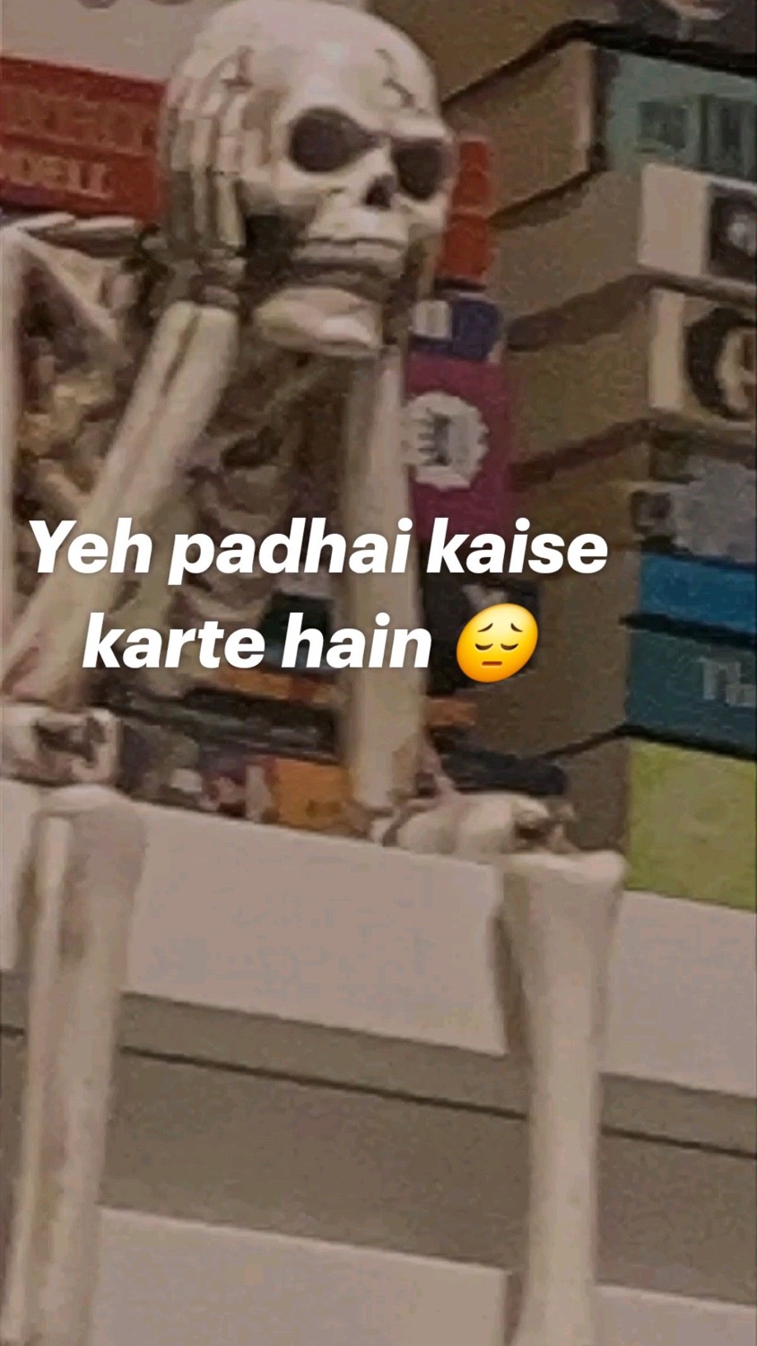 Skeleton slumped at a desk with its head in its hands: 'Yeh padhai kaise karte hain 😮‍💨' (how do people even study)