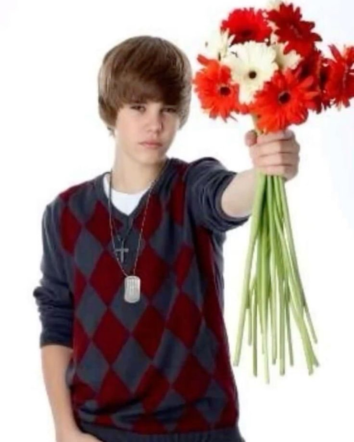 Young Justin Bieber holding out a bouquet of red flowers toward the camera with a neutral expression