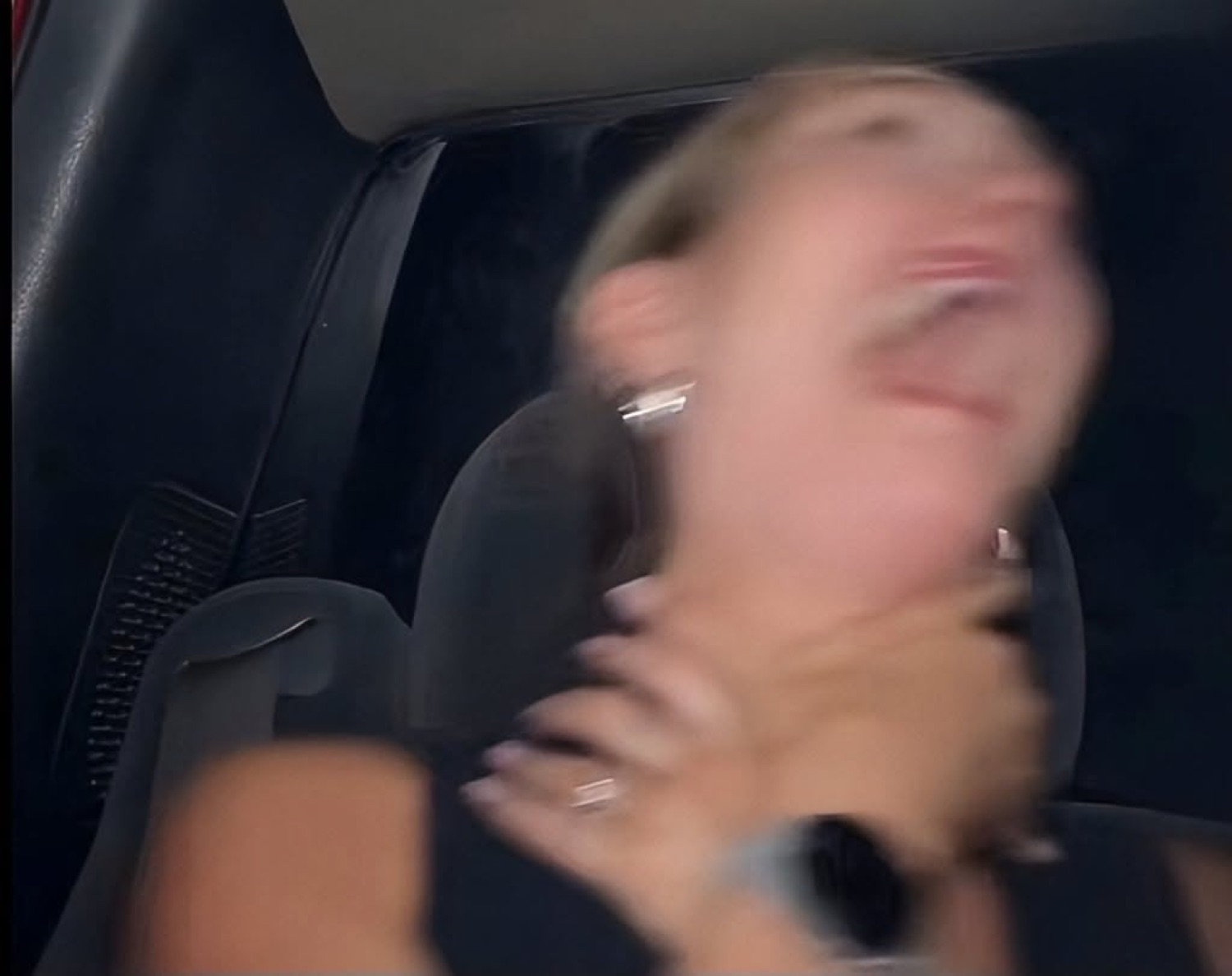 Blurry woman in a car throwing her head back laughing hysterically