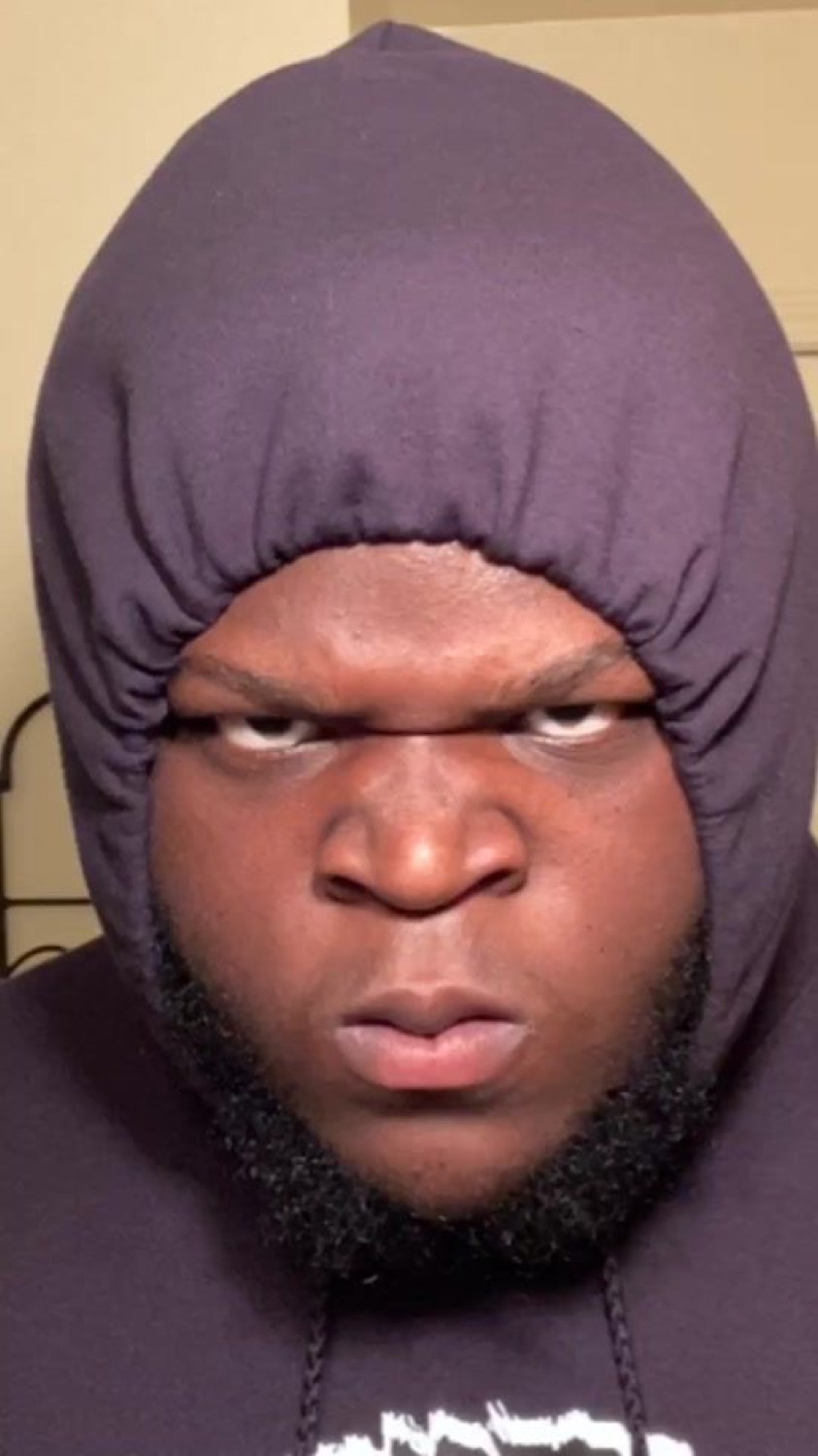 Man in a tight hood glaring at the camera with a menacing frown