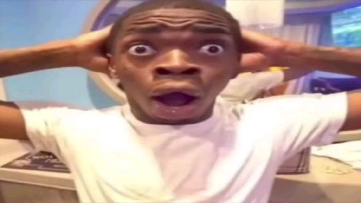 Young man clutching his head with wide shocked eyes