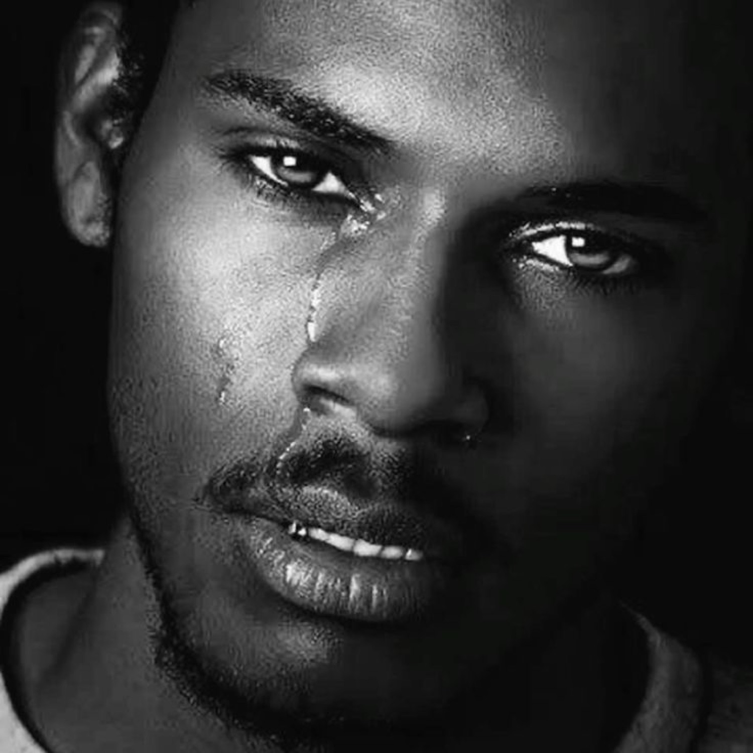 Black and white close-up of a man with a single tear rolling down his cheek