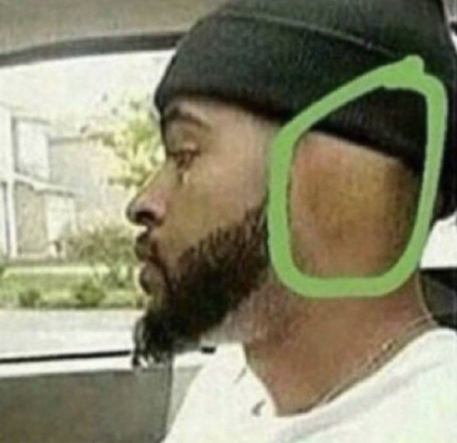 Bearded man in a beanie staring blankly out a car window with a single tear circled in green