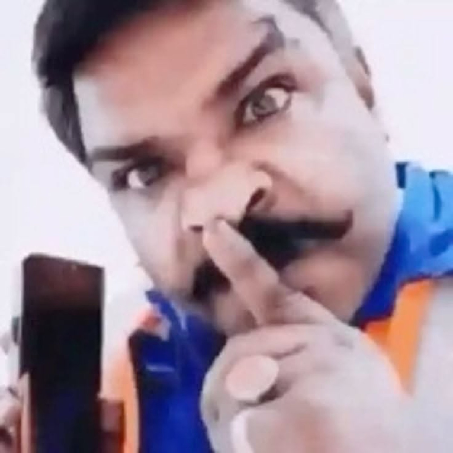Man shushing with a finger and a phone
