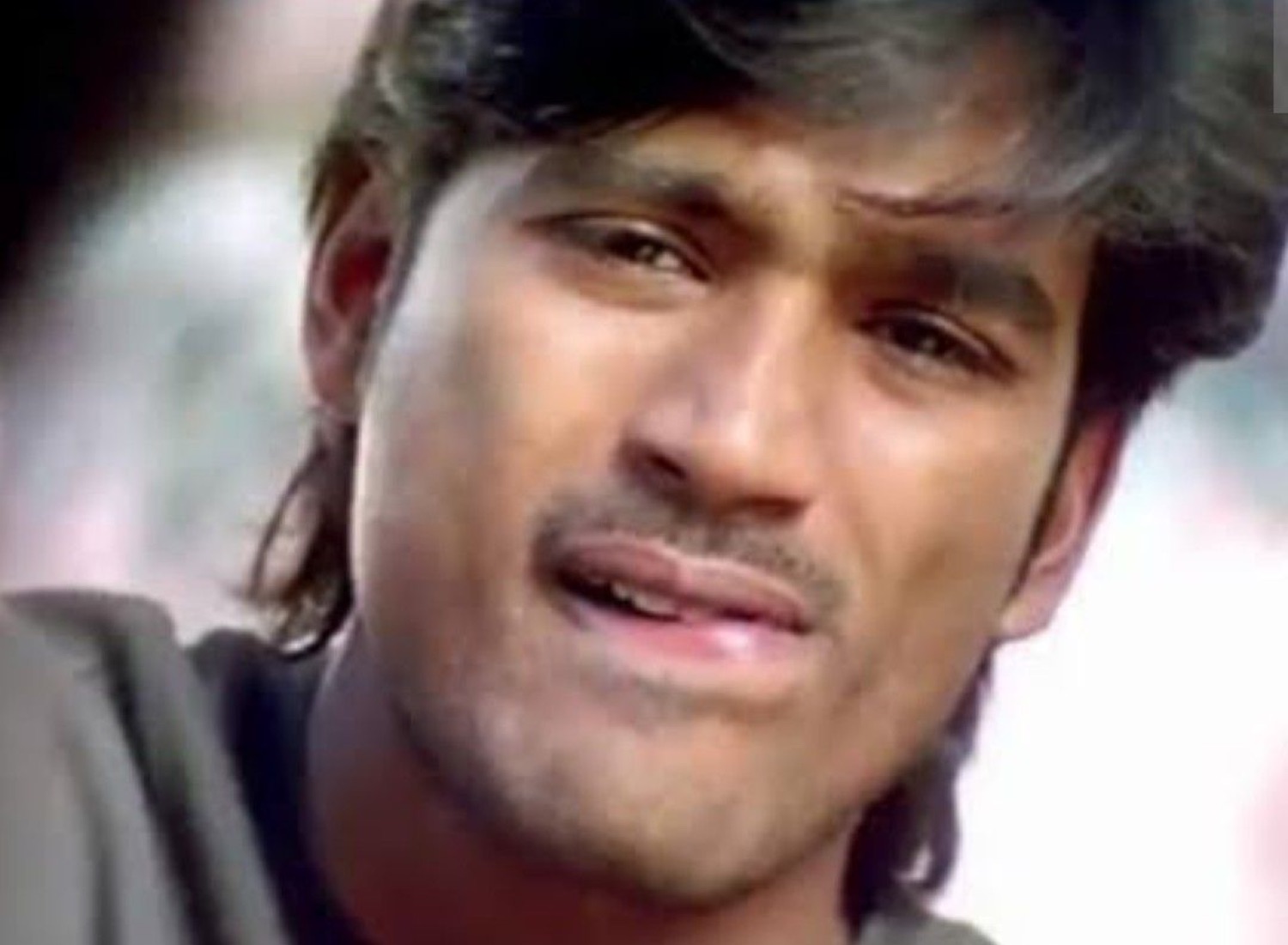 Dhanush squinting with a disappointed grimace