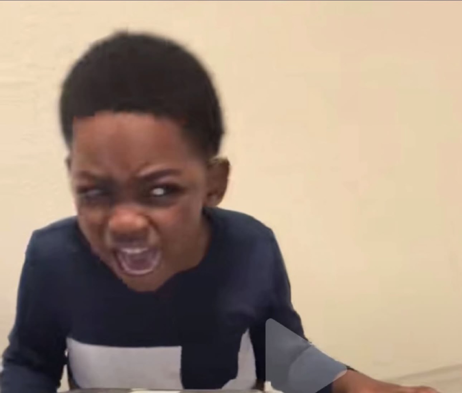 Young boy scrunching his face and yelling with intense frustration