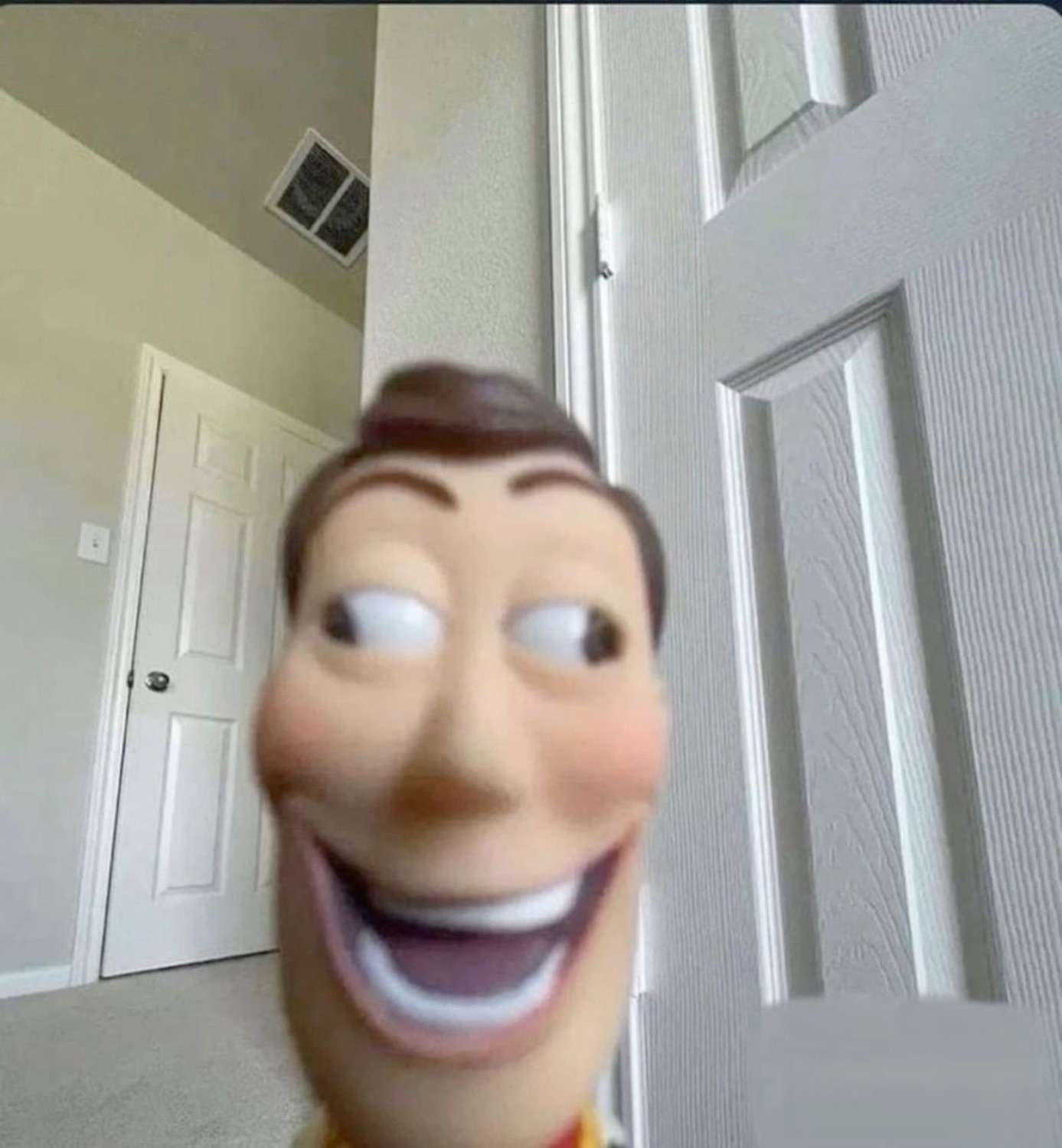 Woody from Toy Story face edited onto a person, grinning creepily in a hallway