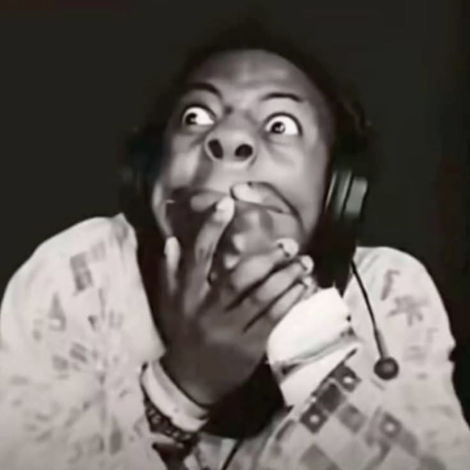 Person in headphones covering their mouth with wide, terrified eyes