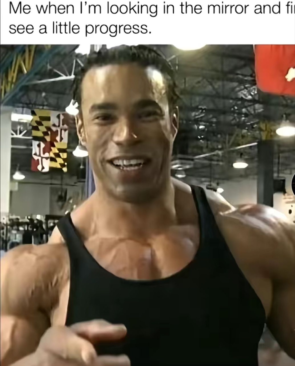 Grinning bodybuilder pointing at the mirror: 'Me when I'm looking in the mirror and finally see a little progress'