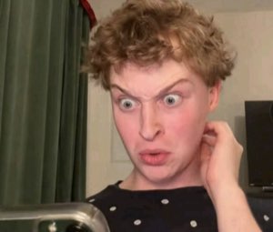 Person with wide eyes and raised brows pulling a shocked, disgusted grimace at the camera