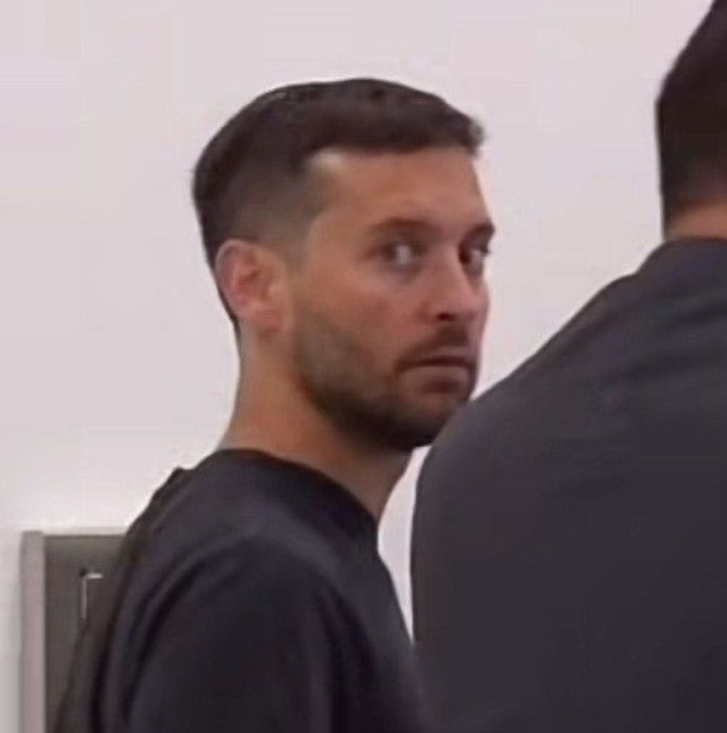 Man glancing back over his shoulder with a wary side-eye