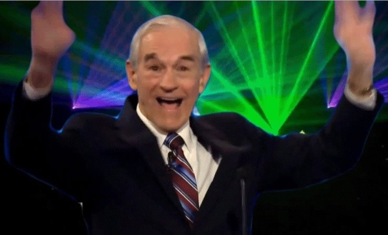 Older man throwing both arms up in wild excitement in front of a laser light show