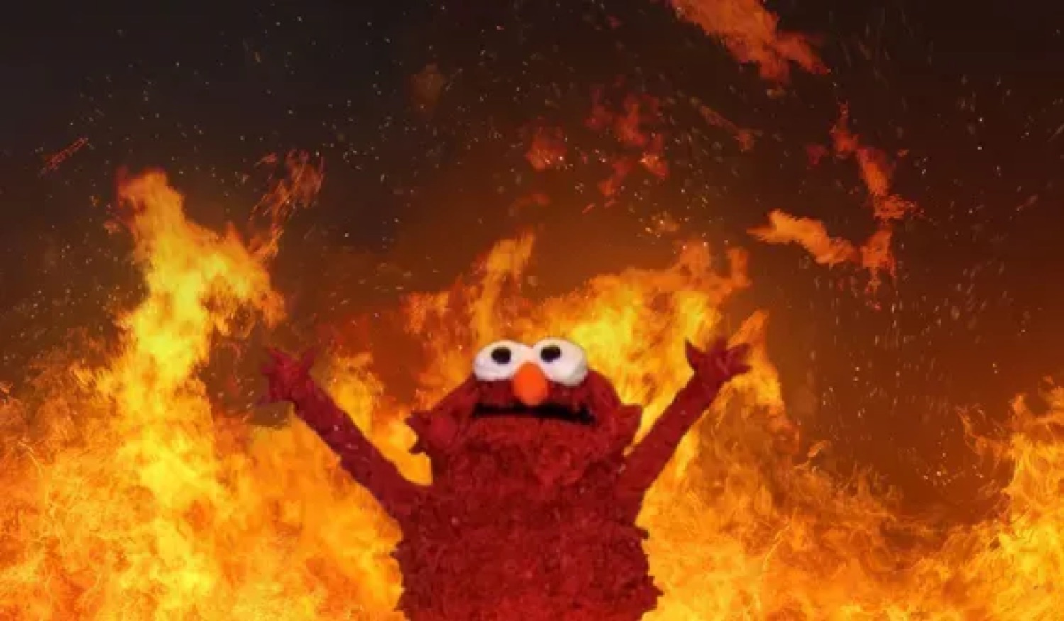 Elmo raising his arms in front of a raging wall of fire