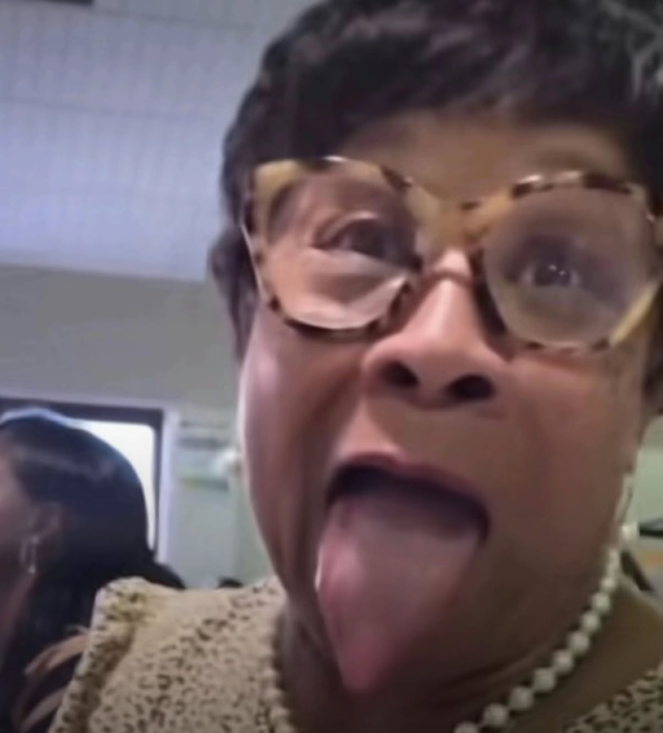 Older woman in big glasses sticking her tongue way out for a goofy dramatic face