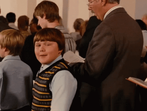 Rowley Jefferson in a striped sweater vest grinning in a crowd
