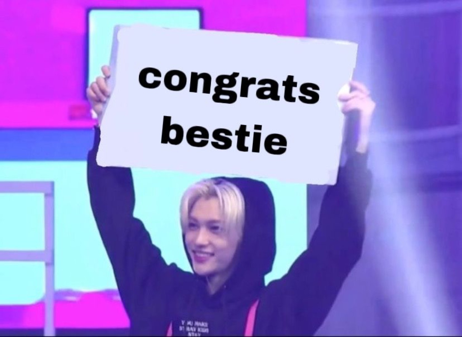 K-pop idol holding up a sign that says 'congrats bestie'