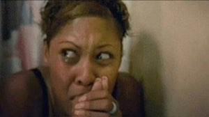 Woman glancing sideways with her hand clamped over her mouth in nervous shock