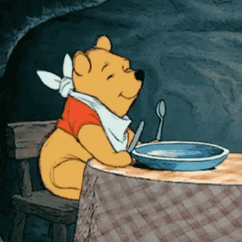 Winnie the Pooh in a bib waiting at the table with an empty bowl