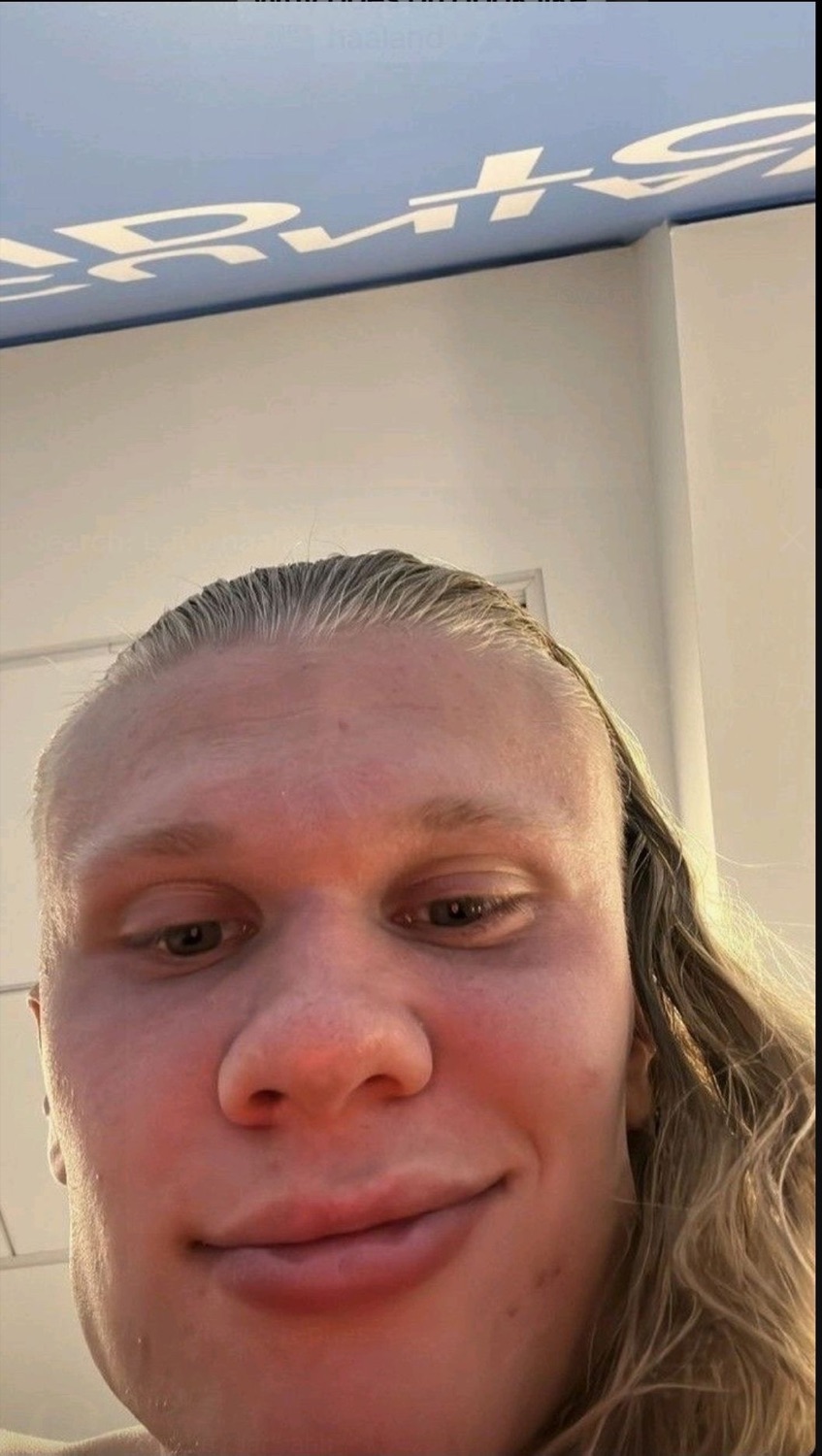 Extreme close-up selfie of a blond man with slicked-back hair and a flat, blank expression