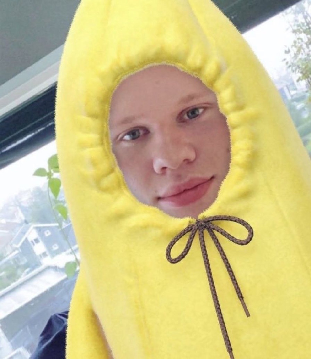 Man wearing a full banana costume with just his flat, unamused face poking through the hood
