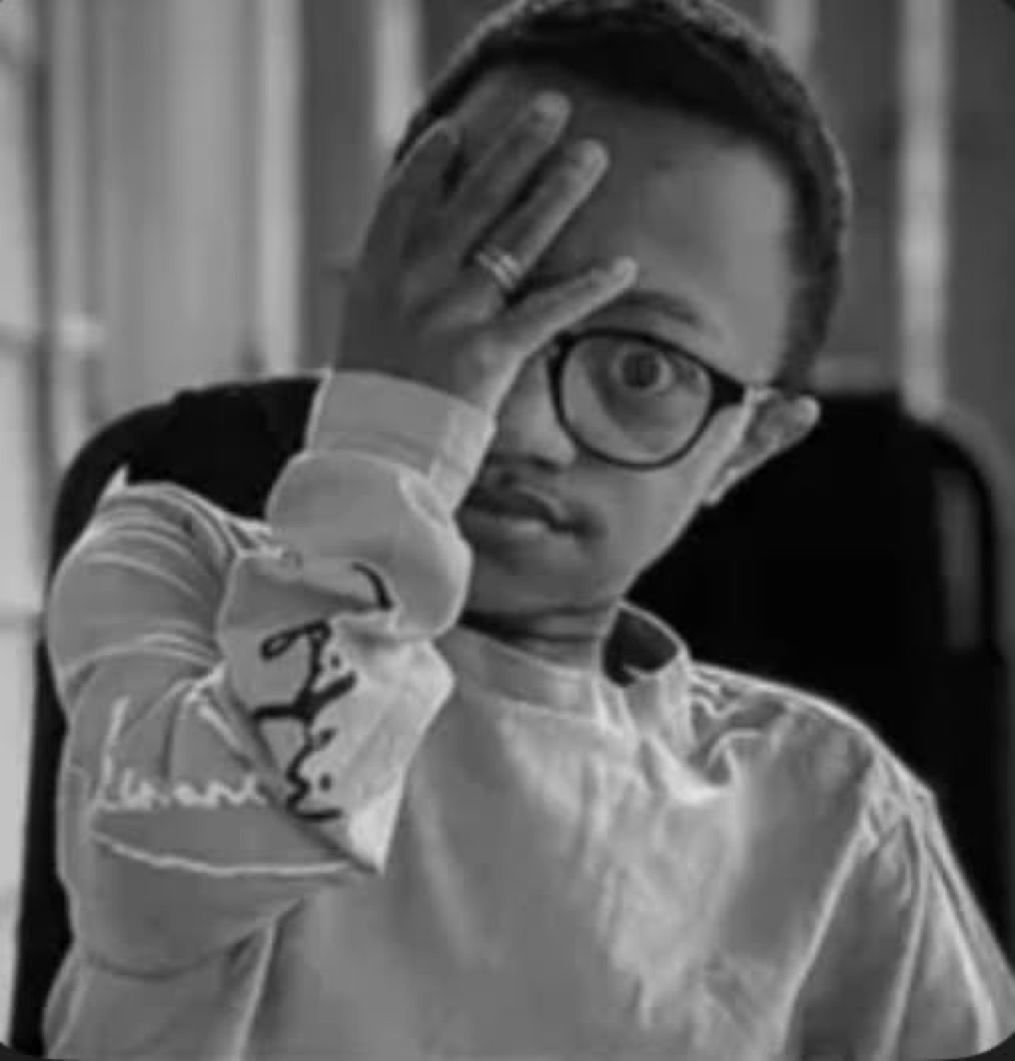 Black-and-white photo of a man covering half his face with his hand