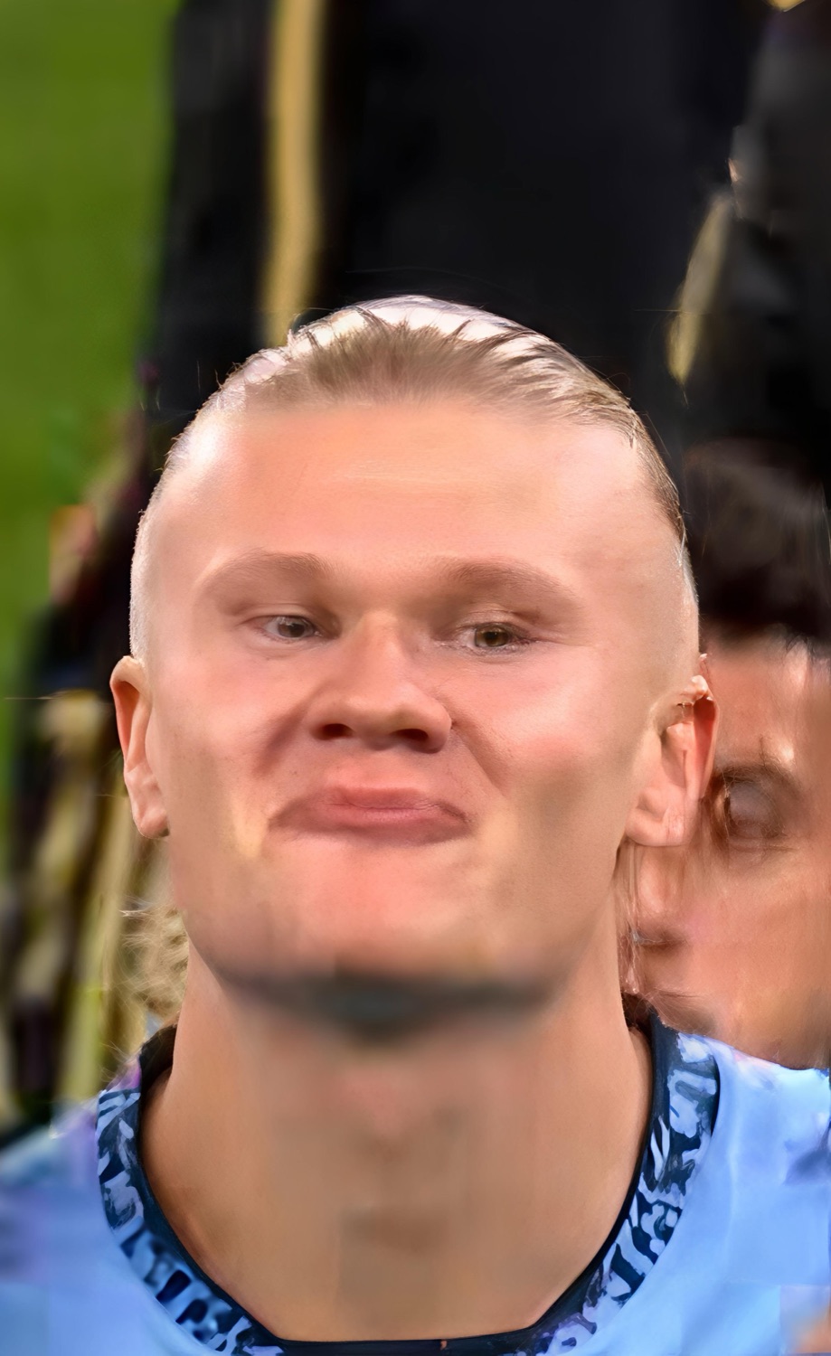 Blond footballer with a slicked-back haircut giving a tight, smug little smirk on the pitch