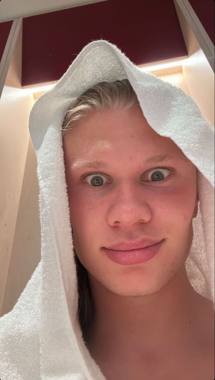 Blond guy with a towel on his head giving a wide-eyed, blank deadpan selfie