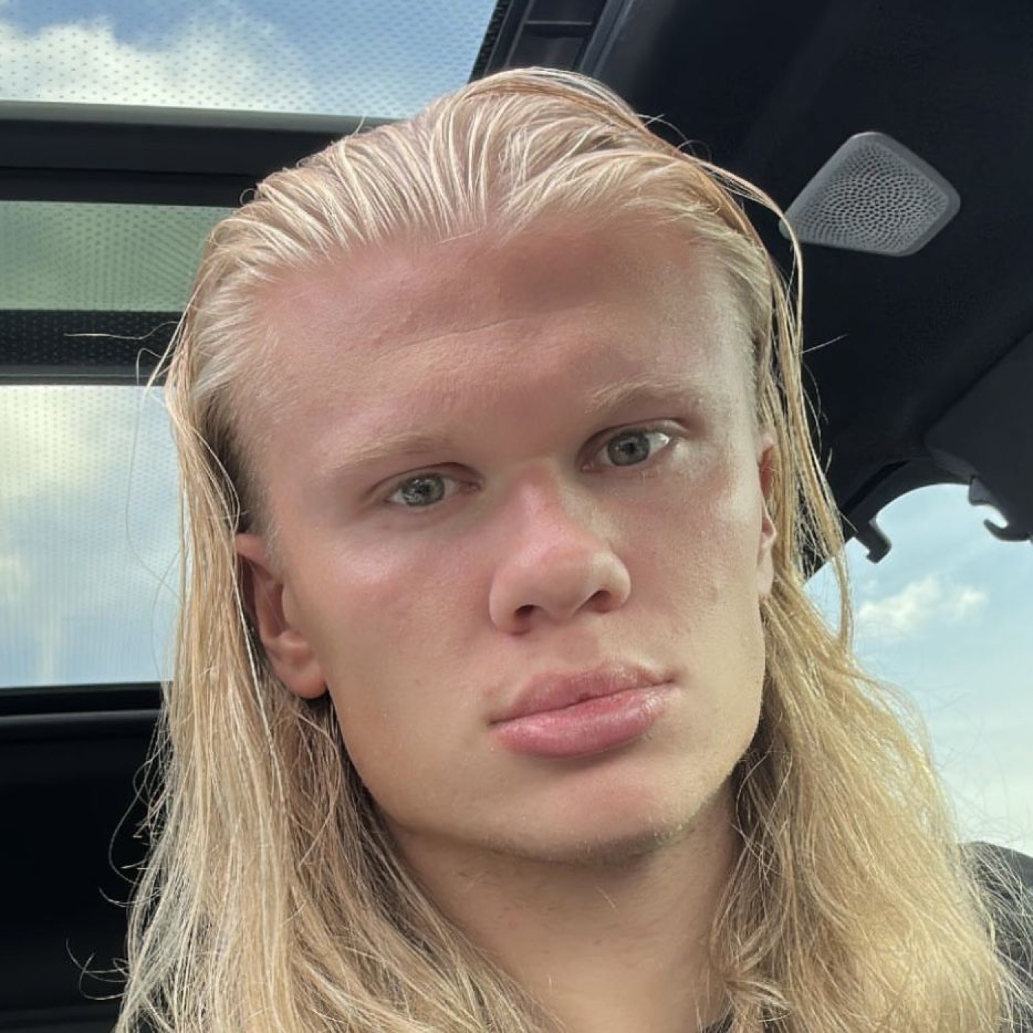 Erling Haaland in a car with damp blond hair, staring forward with a completely blank expression