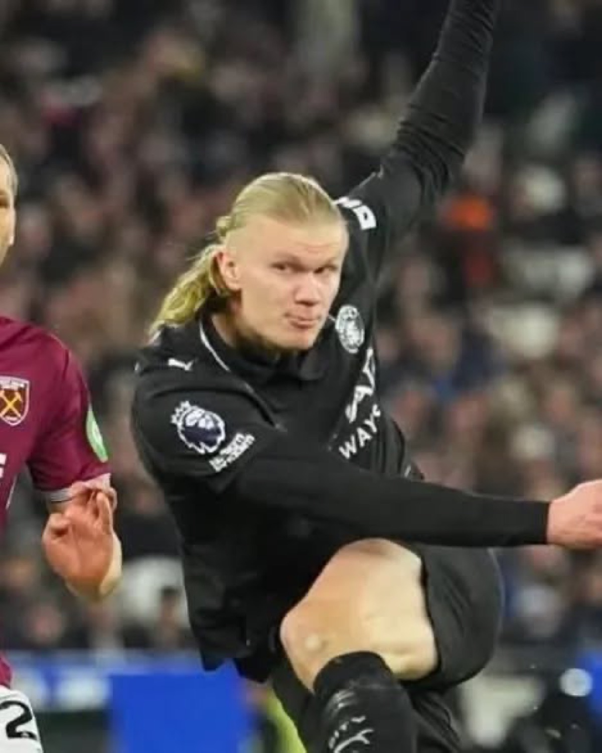 Erling Haaland mid-match with a grimacing scowl, one leg flying high in the air