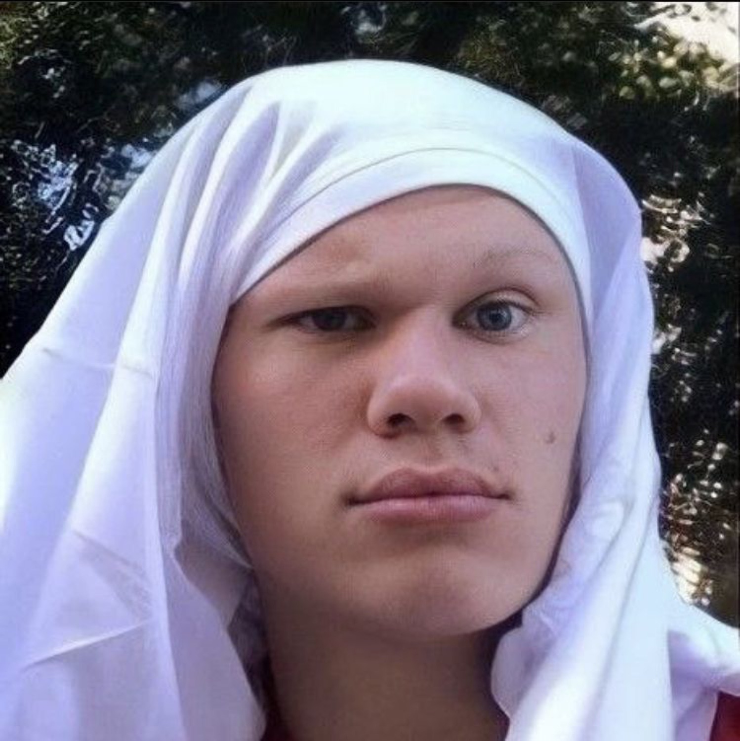 Guy with a white cloth draped over his head giving a flat, serious deadpan look