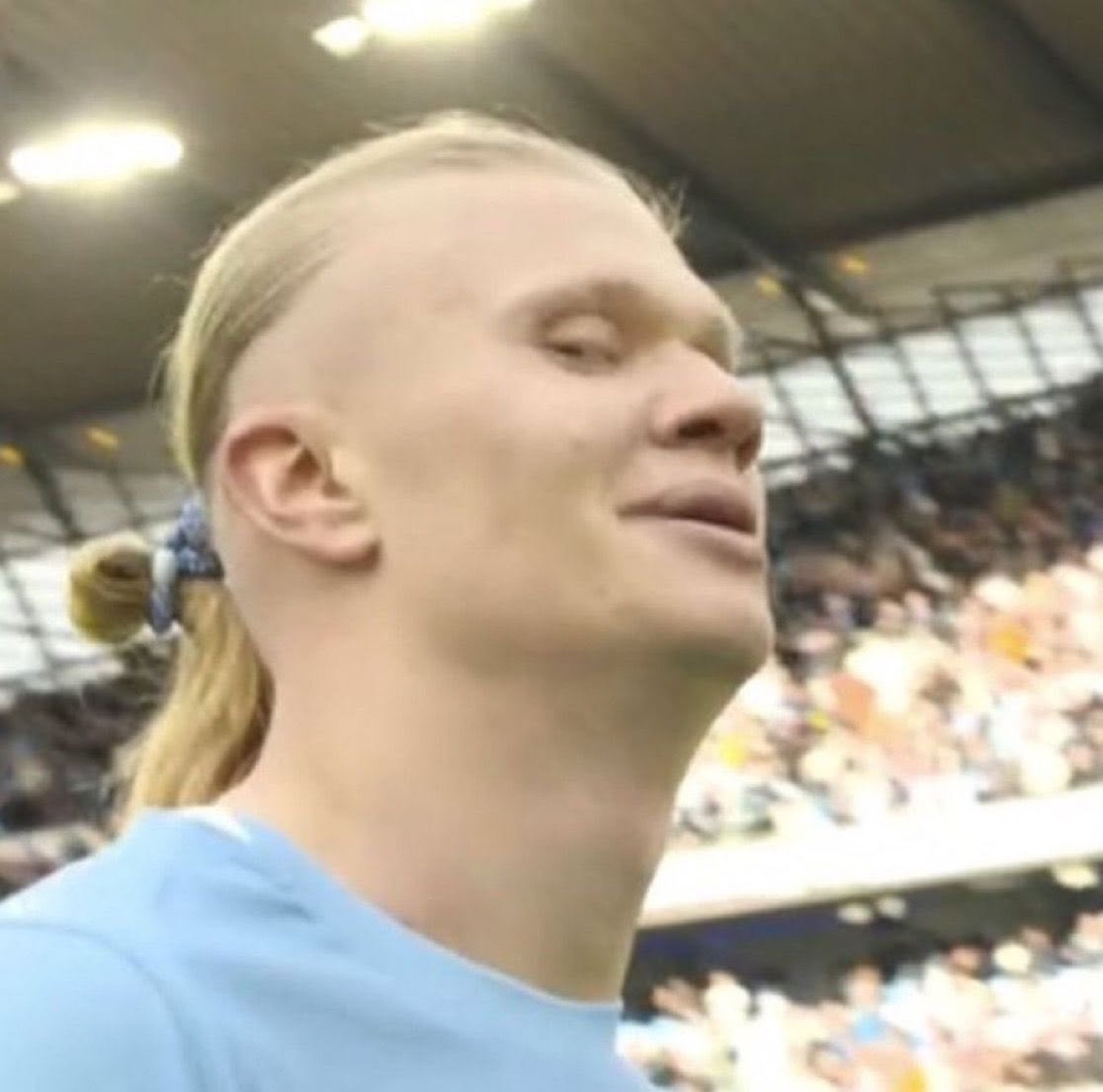 Erling Haaland with eyes closed and a serene smug expression in a stadium crowd