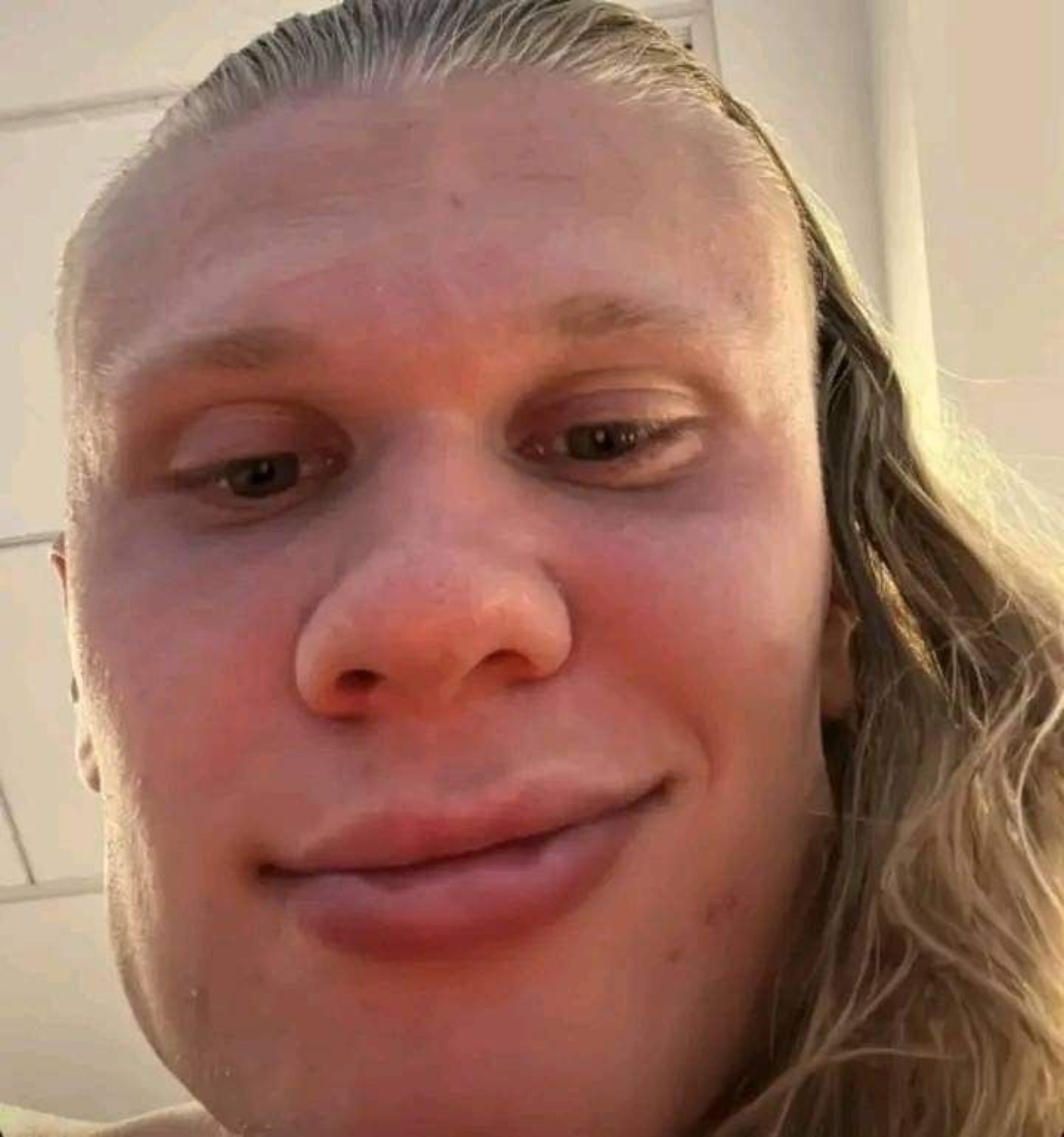 Extreme close-up selfie of a flushed blond man with a completely deadpan face