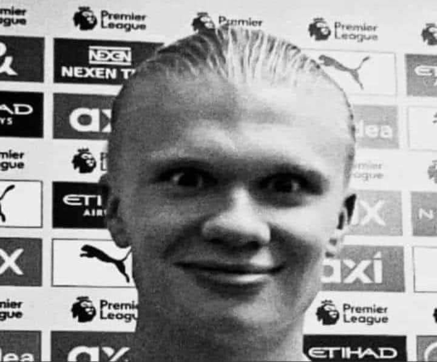 Grainy black-and-white Erling Haaland at a Premier League backdrop wearing a smug little smile