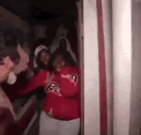 Friends screaming and squeezing through a haunted house doorway
