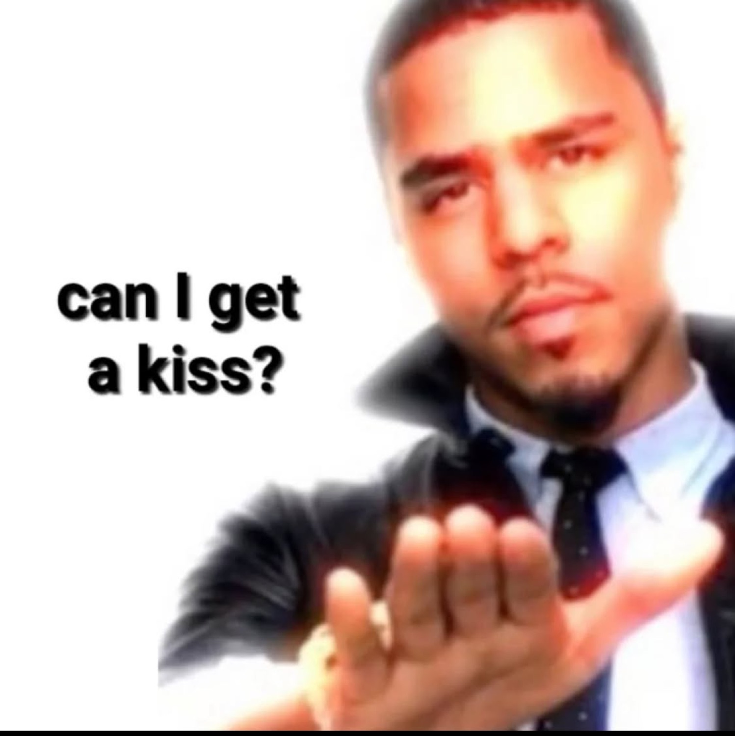 Man in a suit reaching toward camera with a flirty expression captioned 'can I get a kiss?'